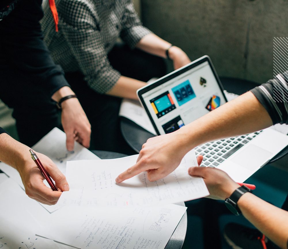 Equipo de emprendedores trabajando junto a una notebook y bocetos sobre la mesa